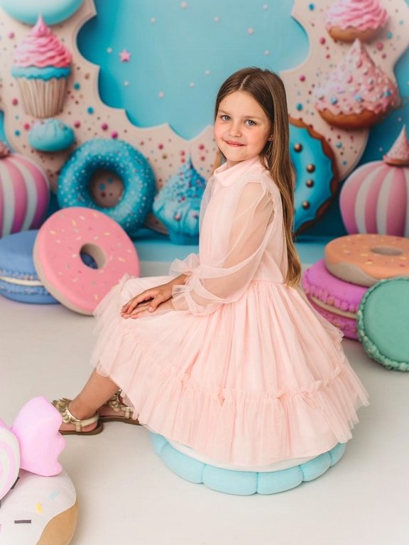 Sukienka wykonana z różowego tiulu dla dziewczynki na cukierkowym tle