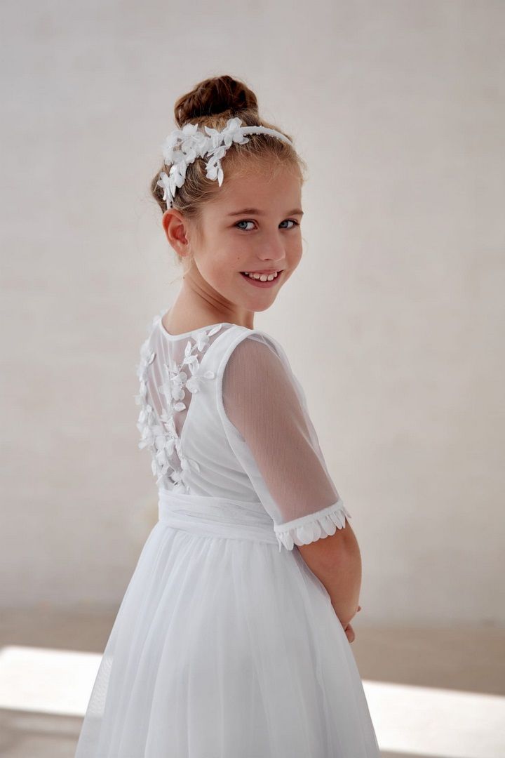 Biała sukienka na komunię z ozdobnymi plecami.
