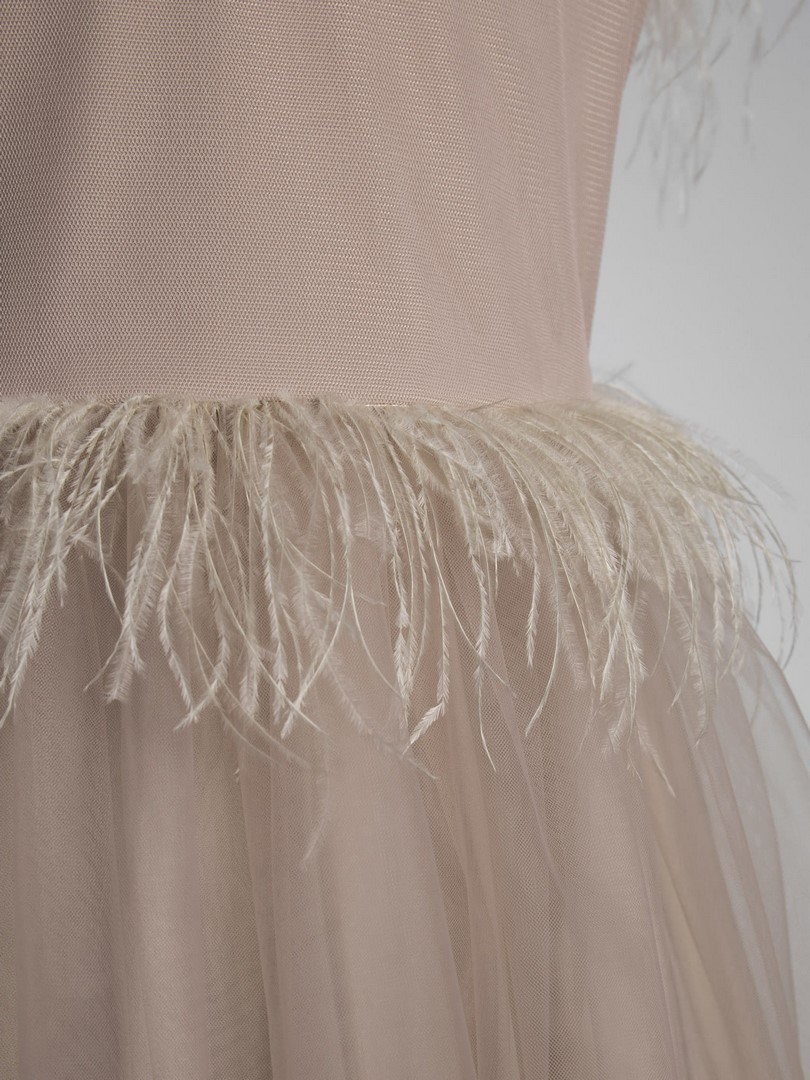 tiulowa sukienka przyozdobiona piorami w bezowym kolorze zblizenie