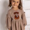 Beżowa sukienka dla dziewczynki z misiem na przodzie, idealna na codzienne wyjścia.