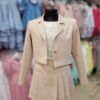 Beżowy komplet składający się z marynarki i szortów, idealny na letnie dni i eleganckie okazje.