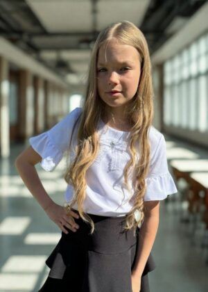 Biała bluzka z falbanami dla dziewczynki, zestawiona z czarną spódniczką. Idealna na letnie wyjścia i uroczystości.