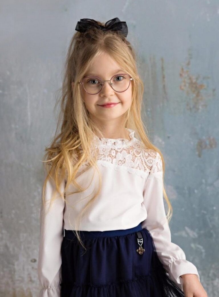 Biała bluzka dla dziewczynki z koronkowym wykończeniem przy szyi, idealna na eleganckie okazje.