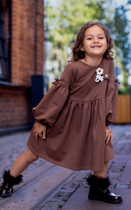 Brązowa bawełniana sukienka na jesień z długimi rękawami i ozdobnym kwiatkiem.
