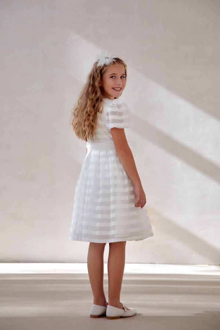 Ecru sukienka w pasy wykonana z organzy, prezentowana na modelce z długimi, kręconymi włosami.