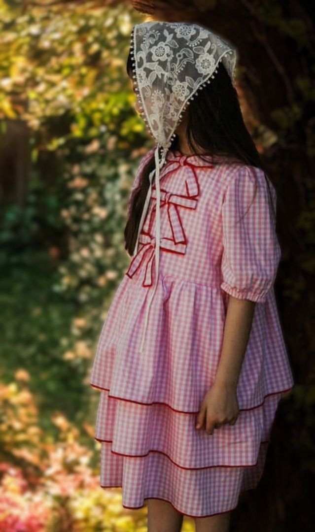 Różowa sukienka w kratkę dla dziewczynki z falbanami i kokardkami, idealna na letnie przyjęcia.