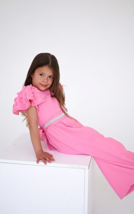 Różowy kombinezon dla dziewczynki z falbanami na rękawach, idealny na letnie przyjęcia.