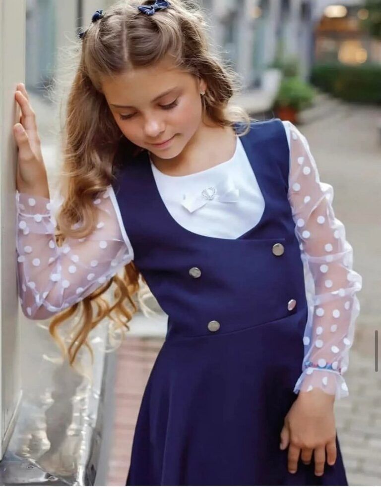 Elegancka sukienka galowa dla dziewczynki w kolorze granatowym z guziczkami i przezroczystymi rękawami w kropki.