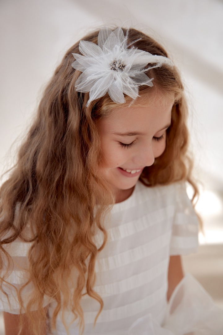 Biała sukienka dla dziewczynki z ozdobną opaską w kształcie kwiatu, idealna na uroczystości.