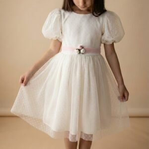 Ecru sukienka w kropki z bufkami i różową wstążką, idealna na specjalne okazje dla dziewczynki.