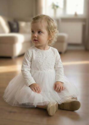 Wizytowa sukienka dla niemowlaka w kolorze białym z koronkowym wykończeniem, idealna na specjalne okazje.