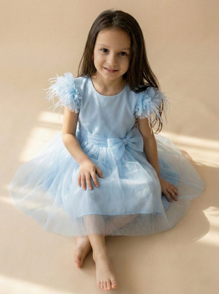 Tiulowa sukienka dla dziewczynki w kolorze niebieskim z ozdobnymi rękawami i kokardą w talii.