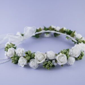 Wianek z białymi różami i zielonymi dodatkami, ozdobiony perłami i wstążką. Idealny na uroczystości i specjalne okazje.